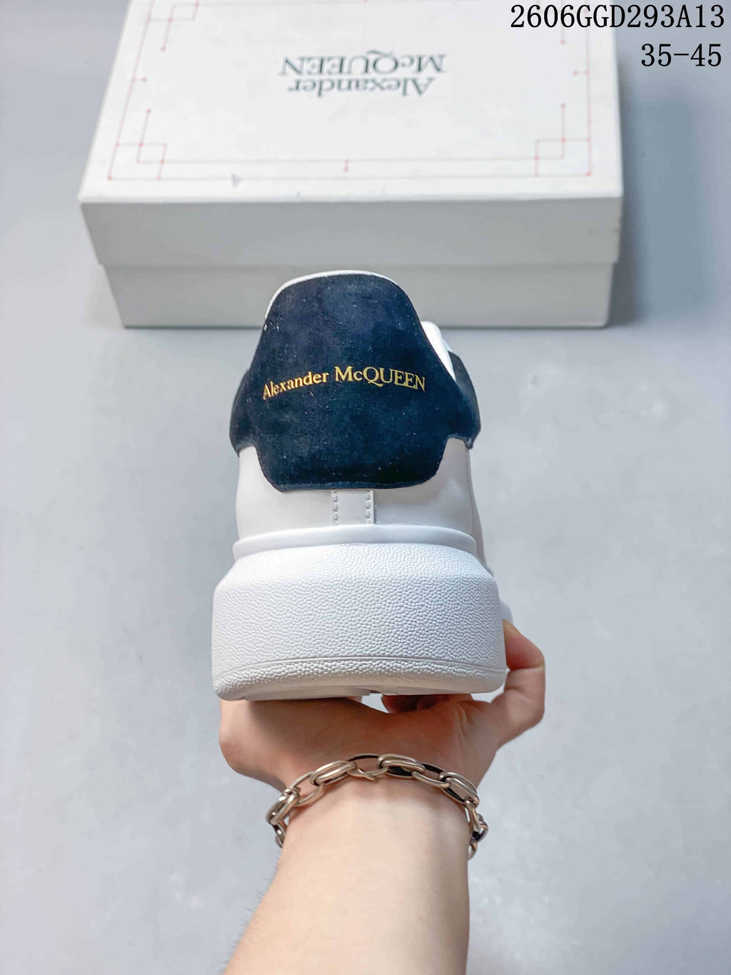 Rear view of a white sneaker with a black heel tab and gold-tone branding
