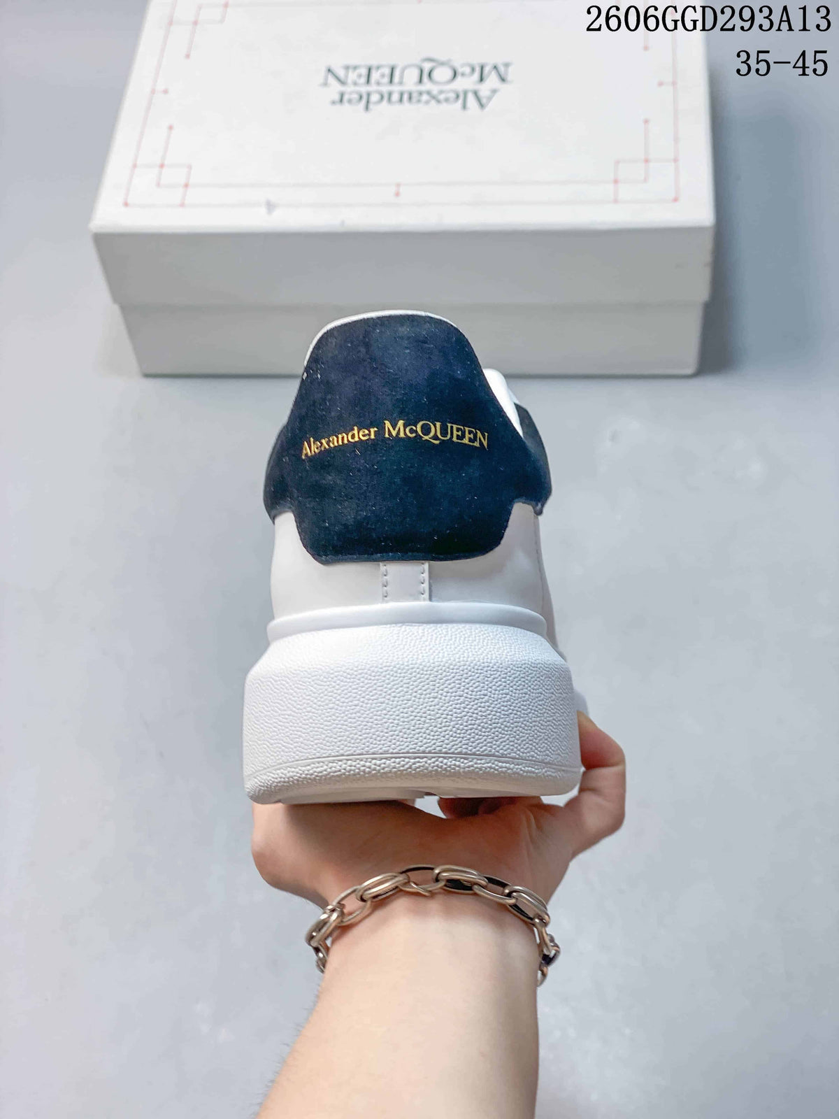 Rear view of a white sneaker with a black heel tab and gold-tone branding