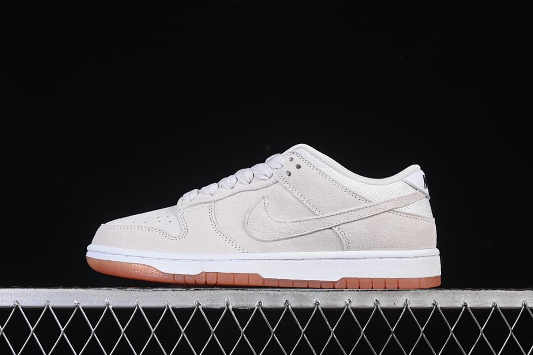 Side profile of light-colored Nike SB Dunk Low sneakers with a white midsole and gum outsole