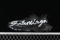 Black Balenciaga Track sneaker with bold white handwriting-style graphics, shown from the side.
