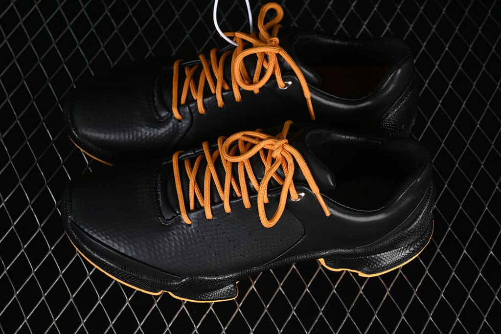Pair of black shoes with orange laces shown from above
