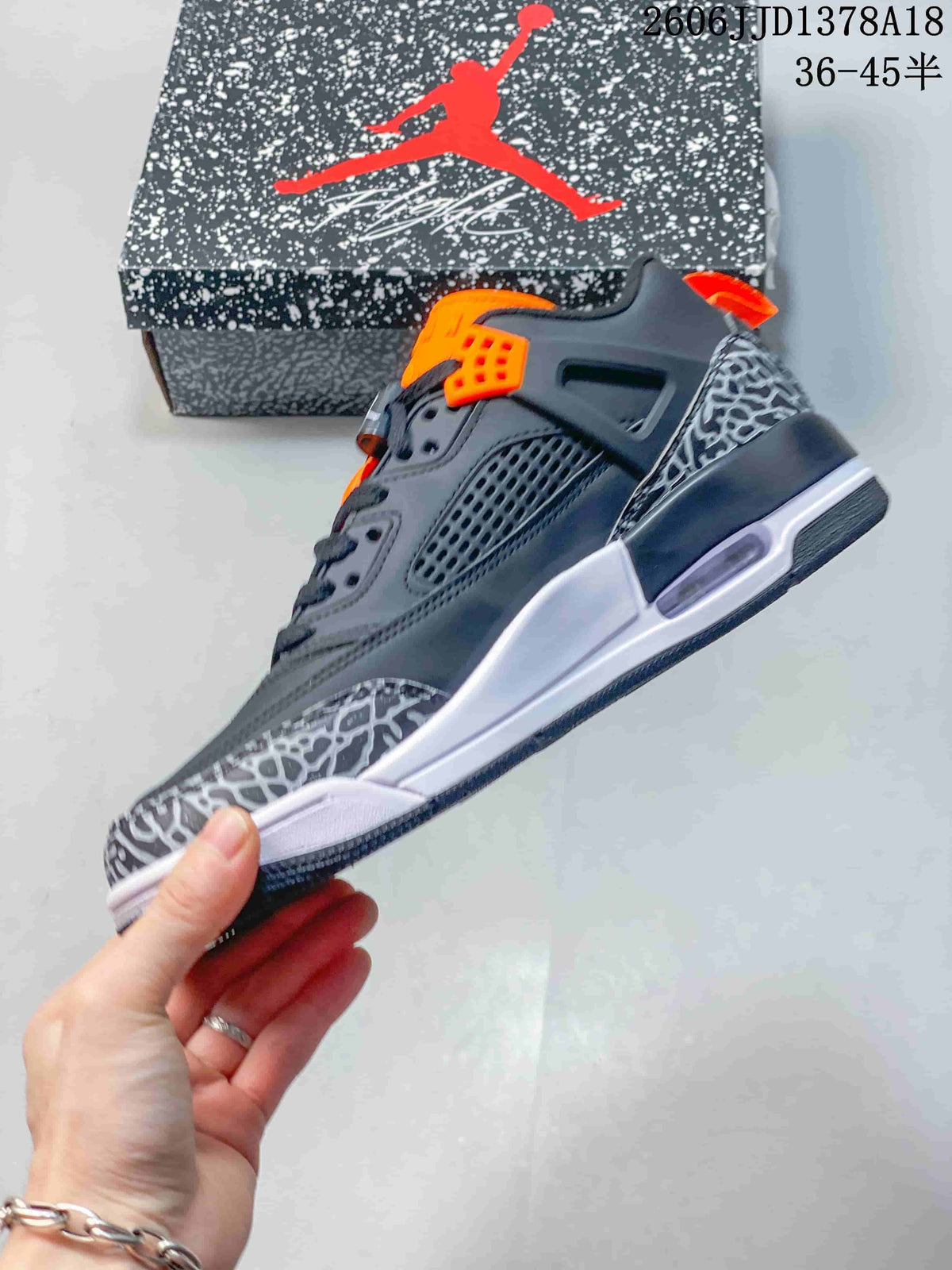 Side view highlighting the dark gray upper, orange lace hardware, elephant-print panels, and white midsole.