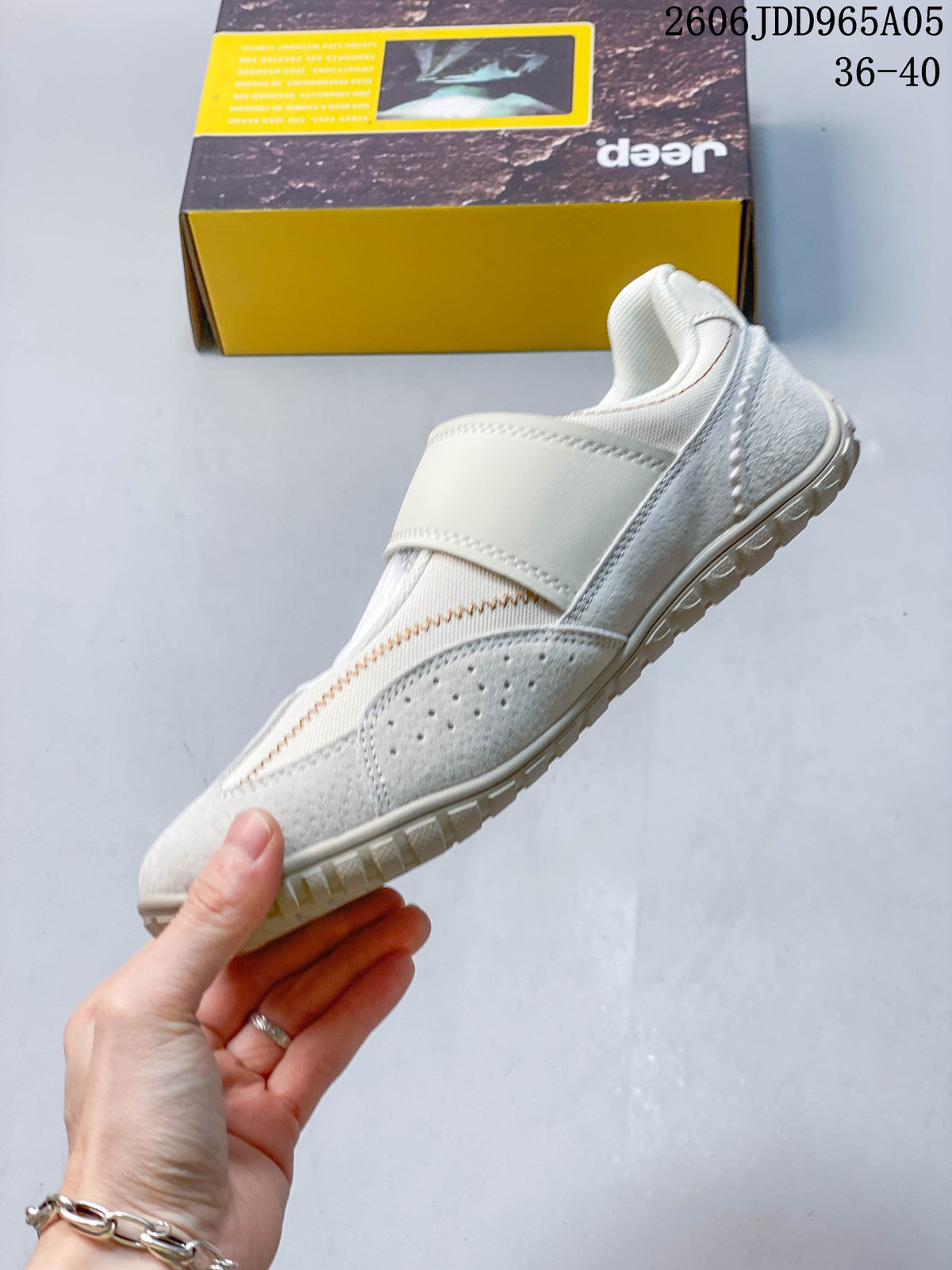 Side view of the cream shoe with strap, perforated panel, and contrast stitching