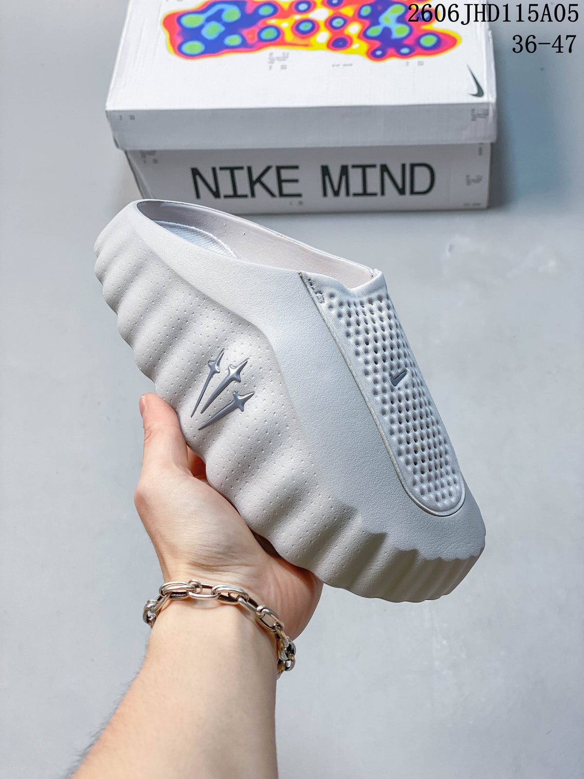 Pale gray Nike Mind slide held in front of a Nike Mind box