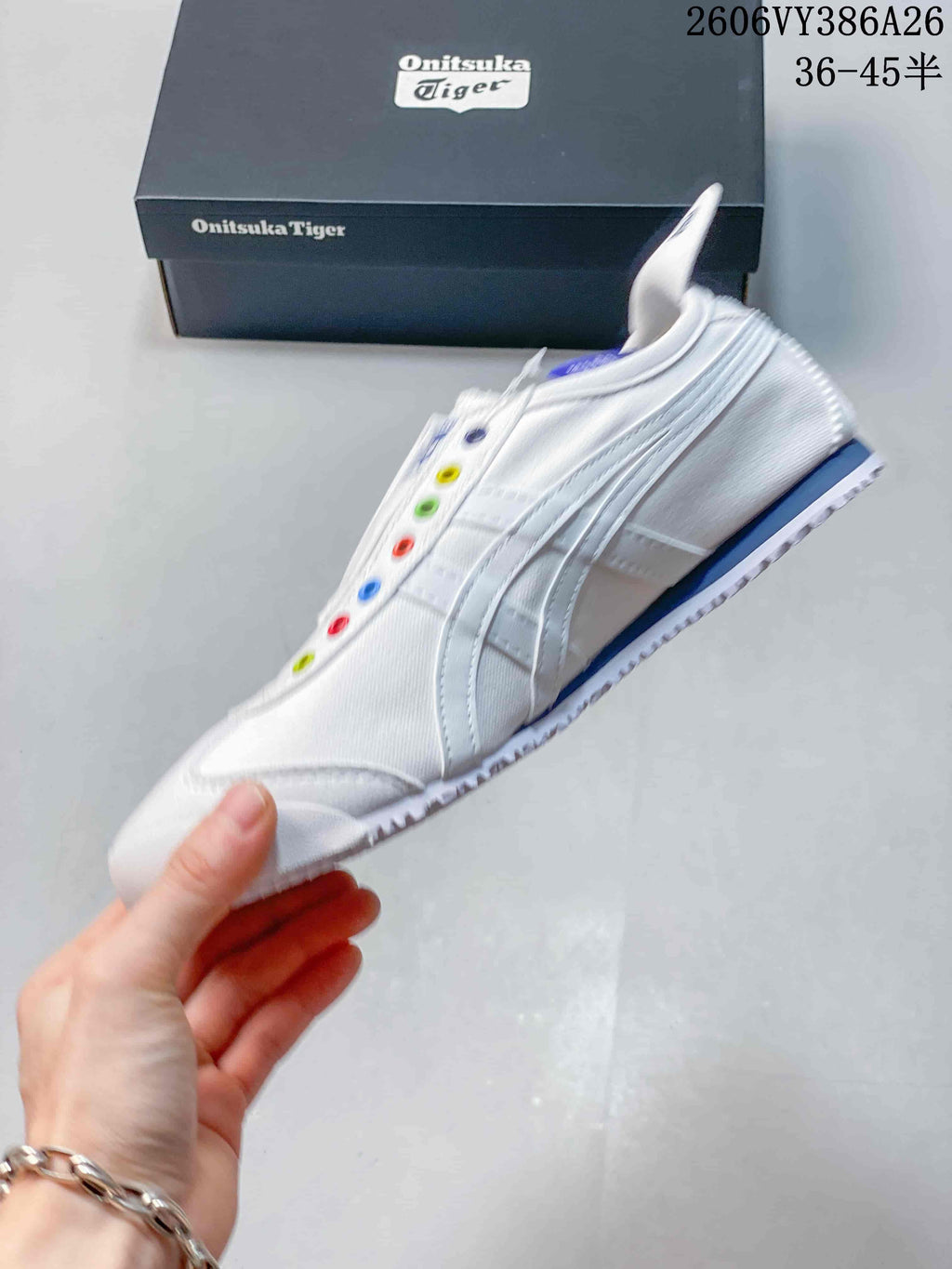 Side view of the white slip-on sneaker with stripe detailing and colorful eyelets