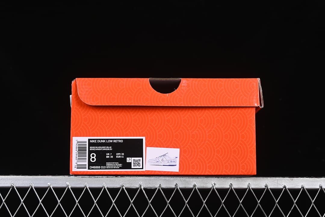 Orange shoe box with a label showing Nike Dunk Low Retro, style code DM6868-010, and sample size EU 41