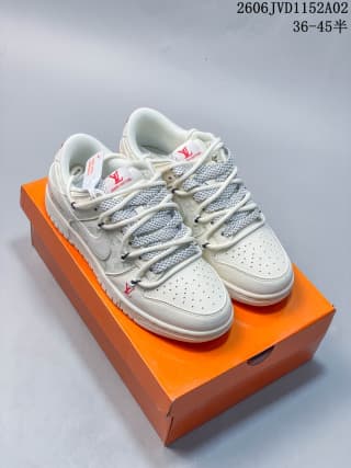 Pair of white low-top sneakers displayed on an orange shoe box, with gray patterned laces and visible red branding details.