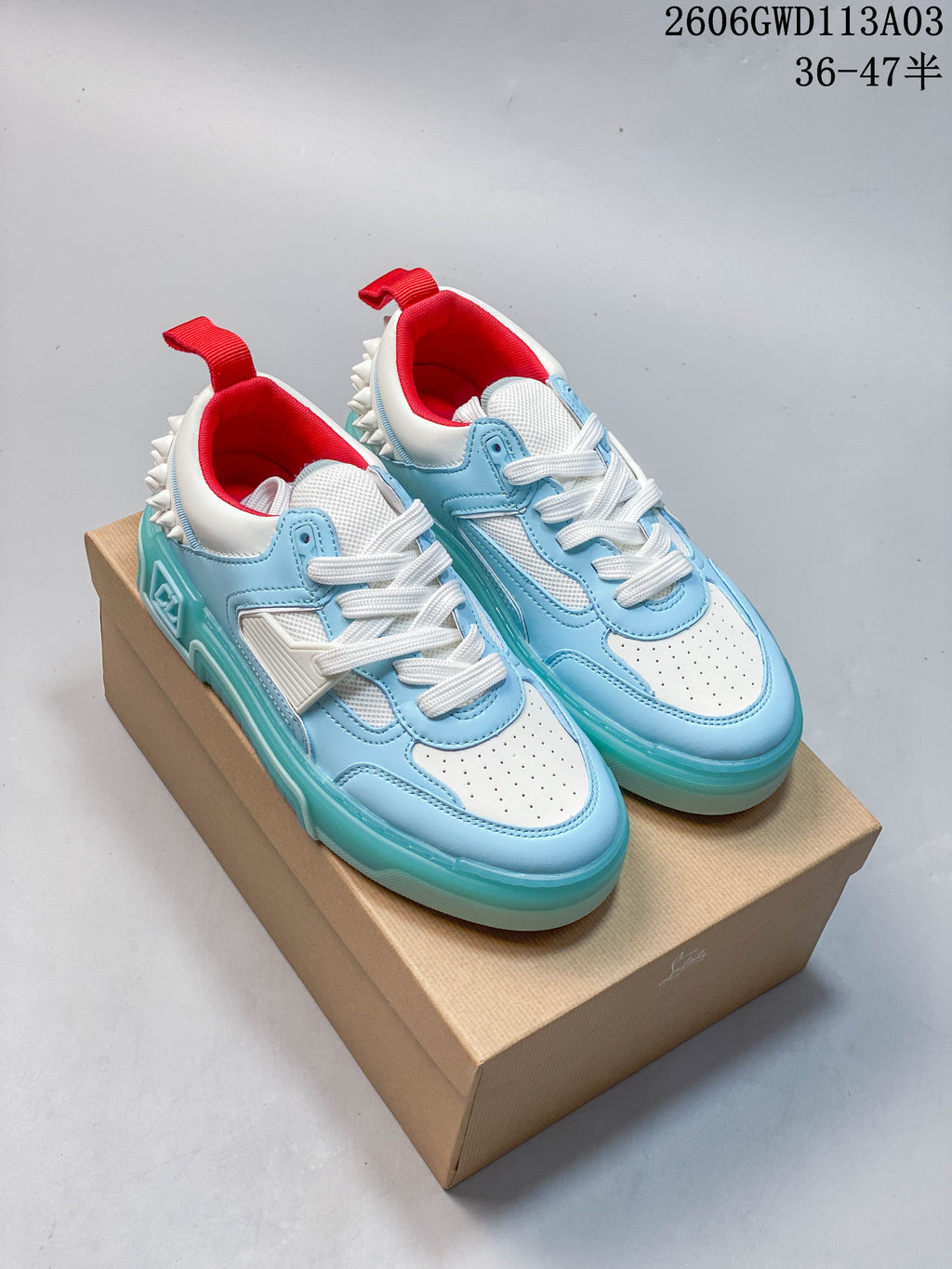 Pair of light blue and white Astroloubi low-top sneakers with red lining, white laces, studded heels, and turquoise-colored soles