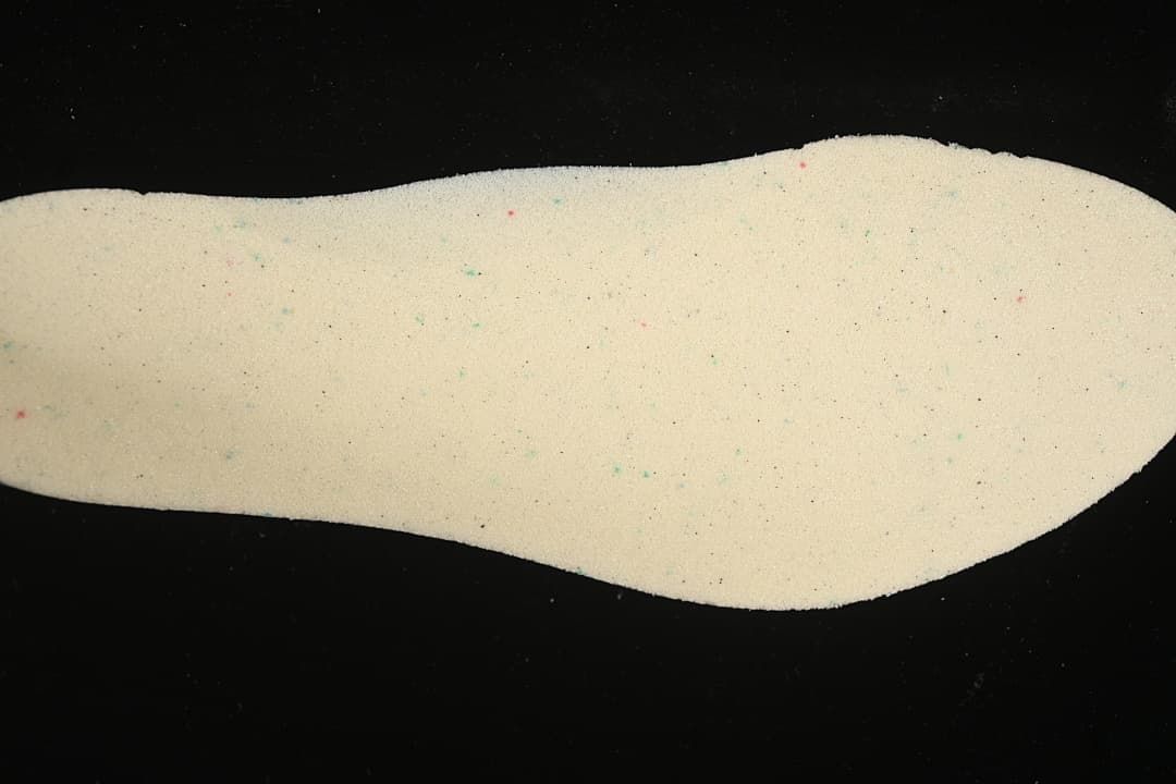 Cream-colored shoe insole shown against a black background