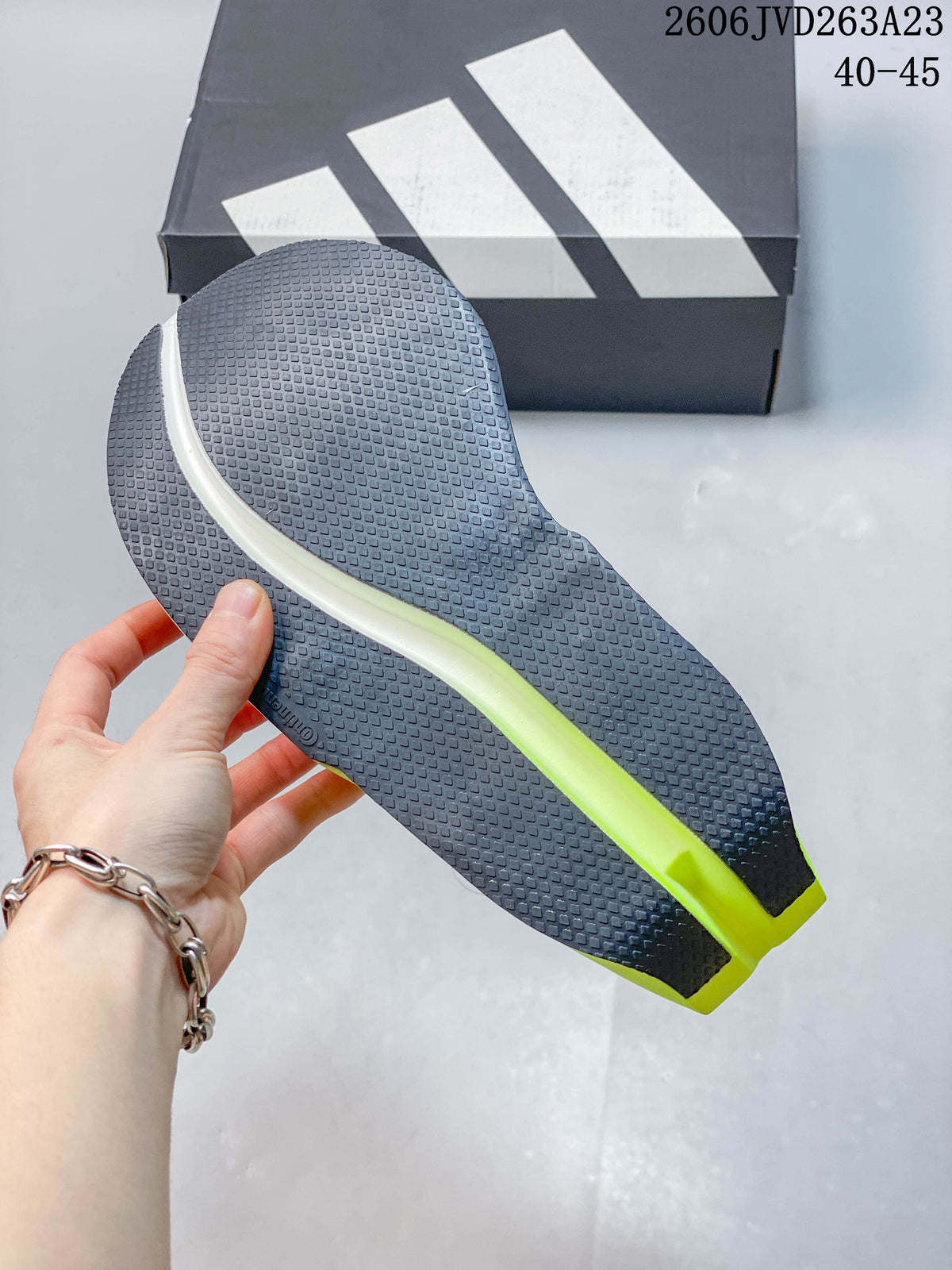Close-up of the shoe outsole, showing a dark textured tread and neon-yellow central detail.
