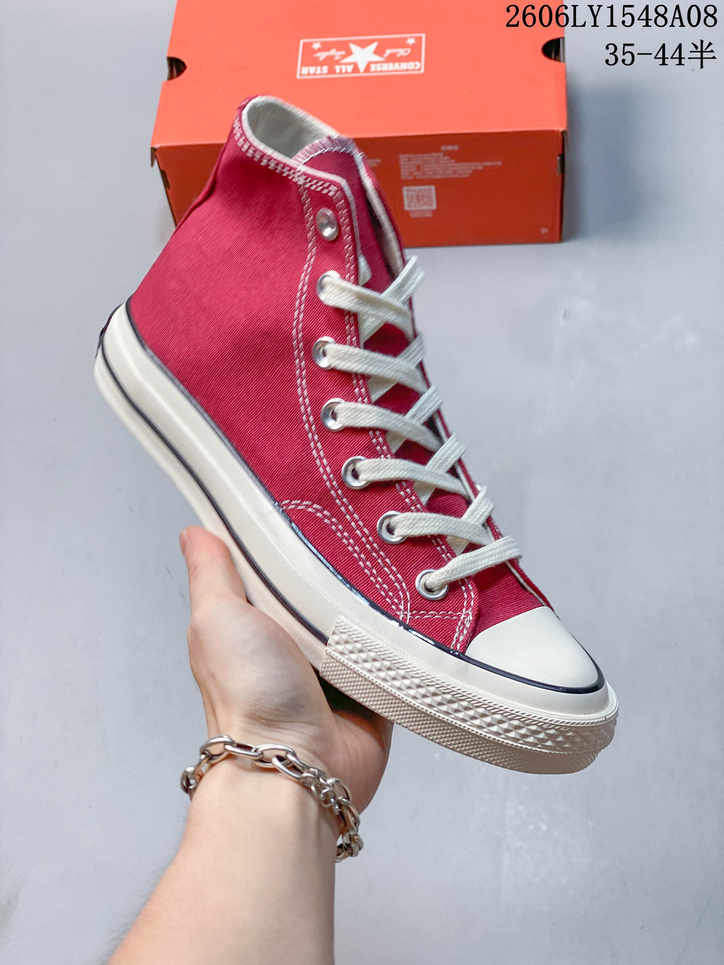 Angled side view of a red Converse high-top sneaker with white laces and an off-white sole.