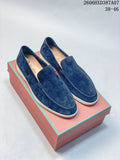Pair of navy slip-on loafers with light-colored soles, shown on a box