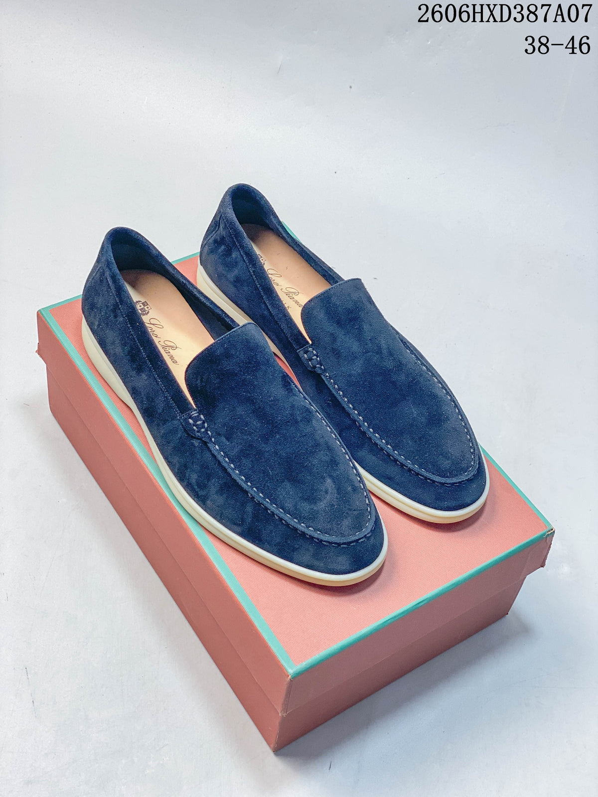Pair of navy slip-on loafers with light-colored soles, shown on a box