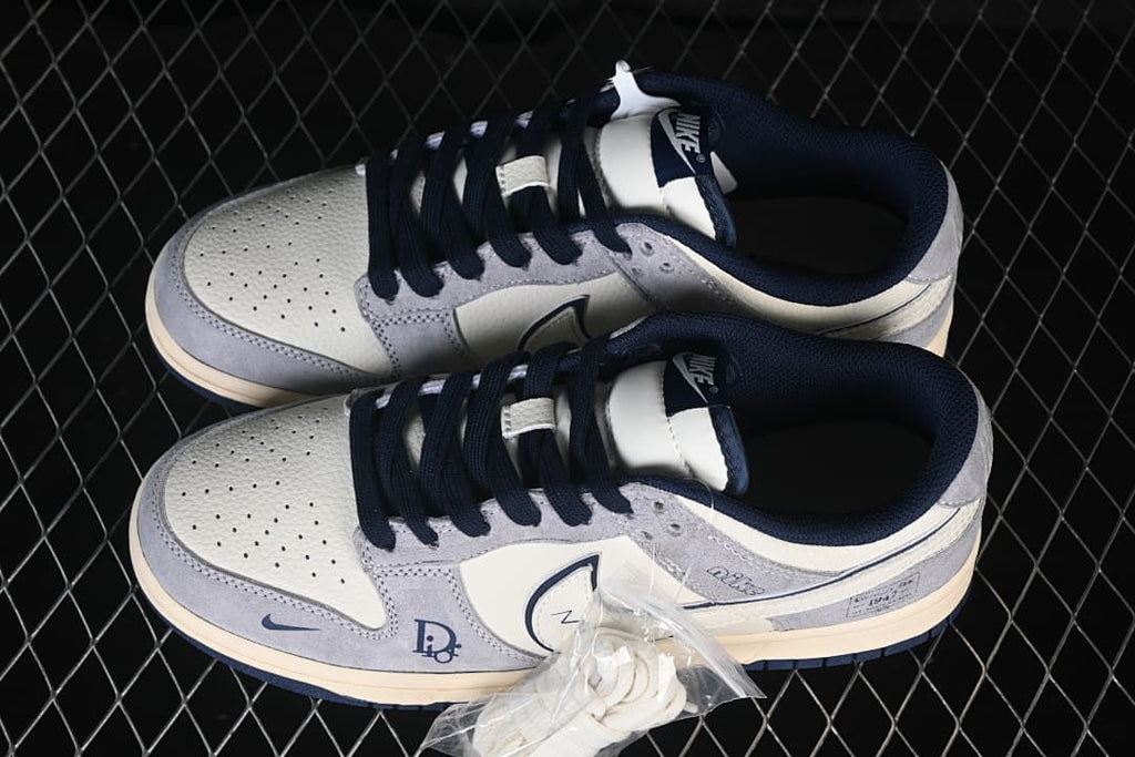 Top view of a pair of grey and white low-top sneakers with navy laces and an extra pair of white laces