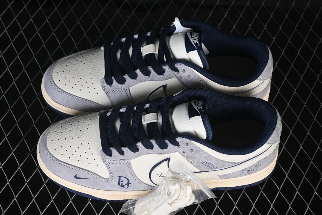 Top view of a pair of grey and white low-top sneakers with navy laces and an extra pair of white laces