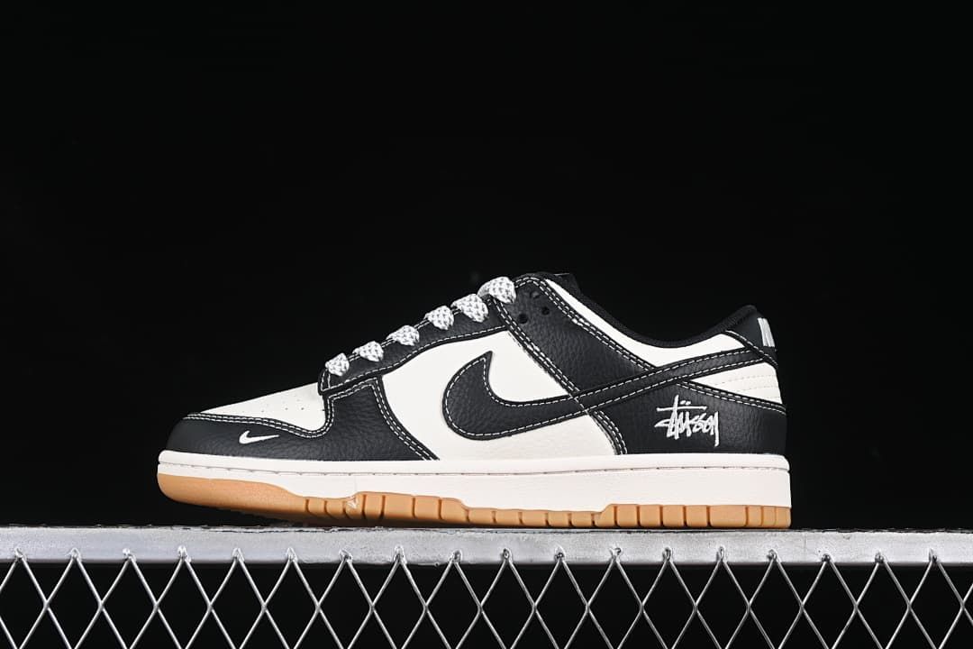 Side view of black and white low-top sneakers with patterned laces, heel script, and gum-colored outsole