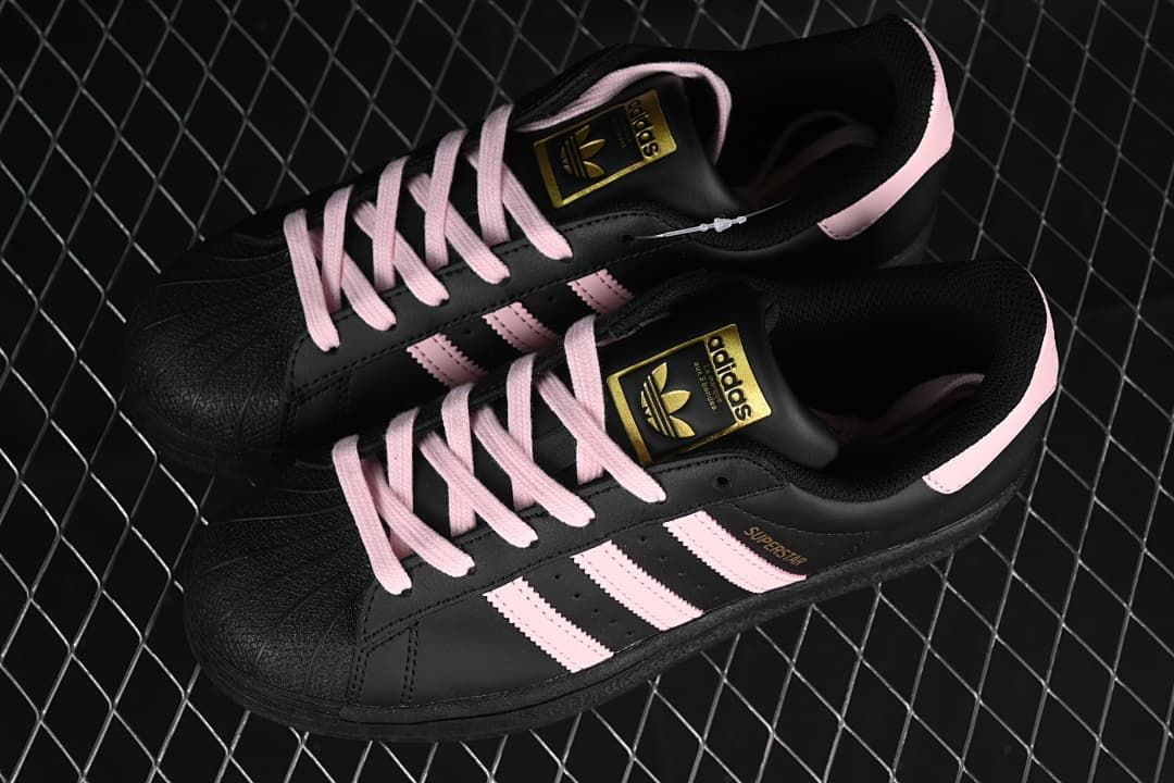 Pair of black and pink adidas Superstar sneakers viewed from above