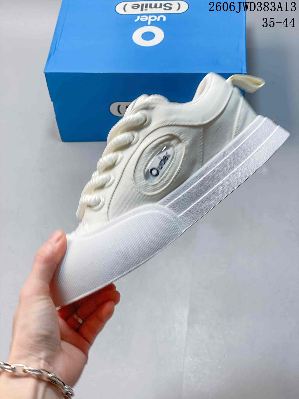 Side profile of the white low-top sneaker showing its layered sole and oval side detail
