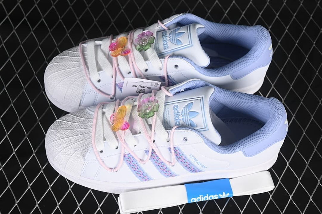 Pair of white Superstar II sneakers with pastel accents and decorative lace charms