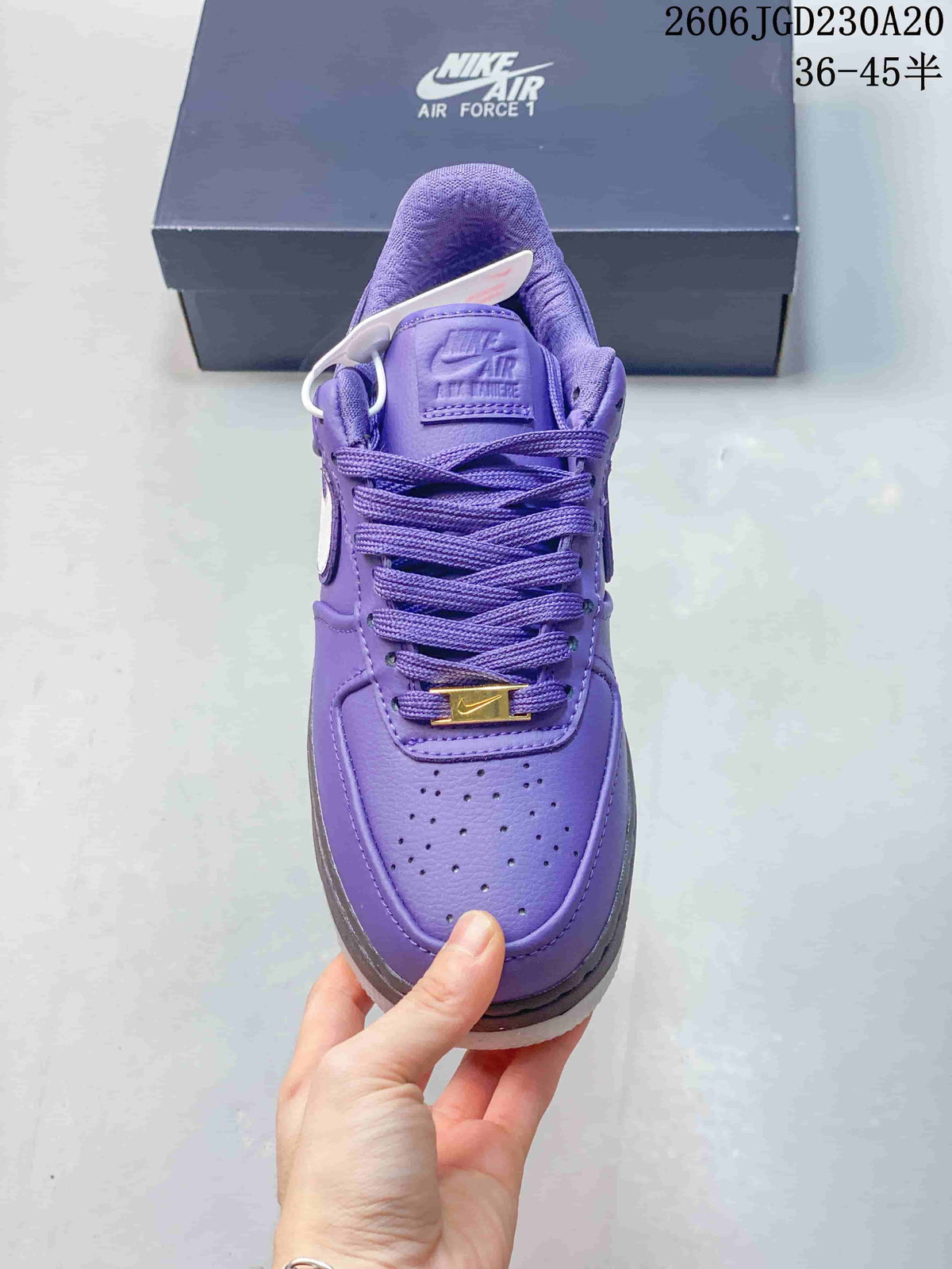 Front view of a purple Nike Air Force 1 sneaker with a perforated toe and gold-tone lace detail