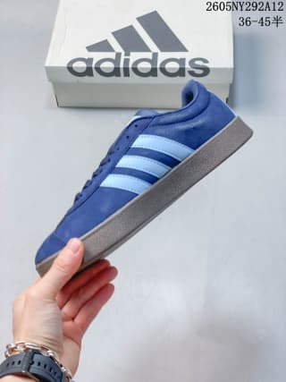 Side profile of the blue sneaker with white stripes and a light brown gum-style outsole.