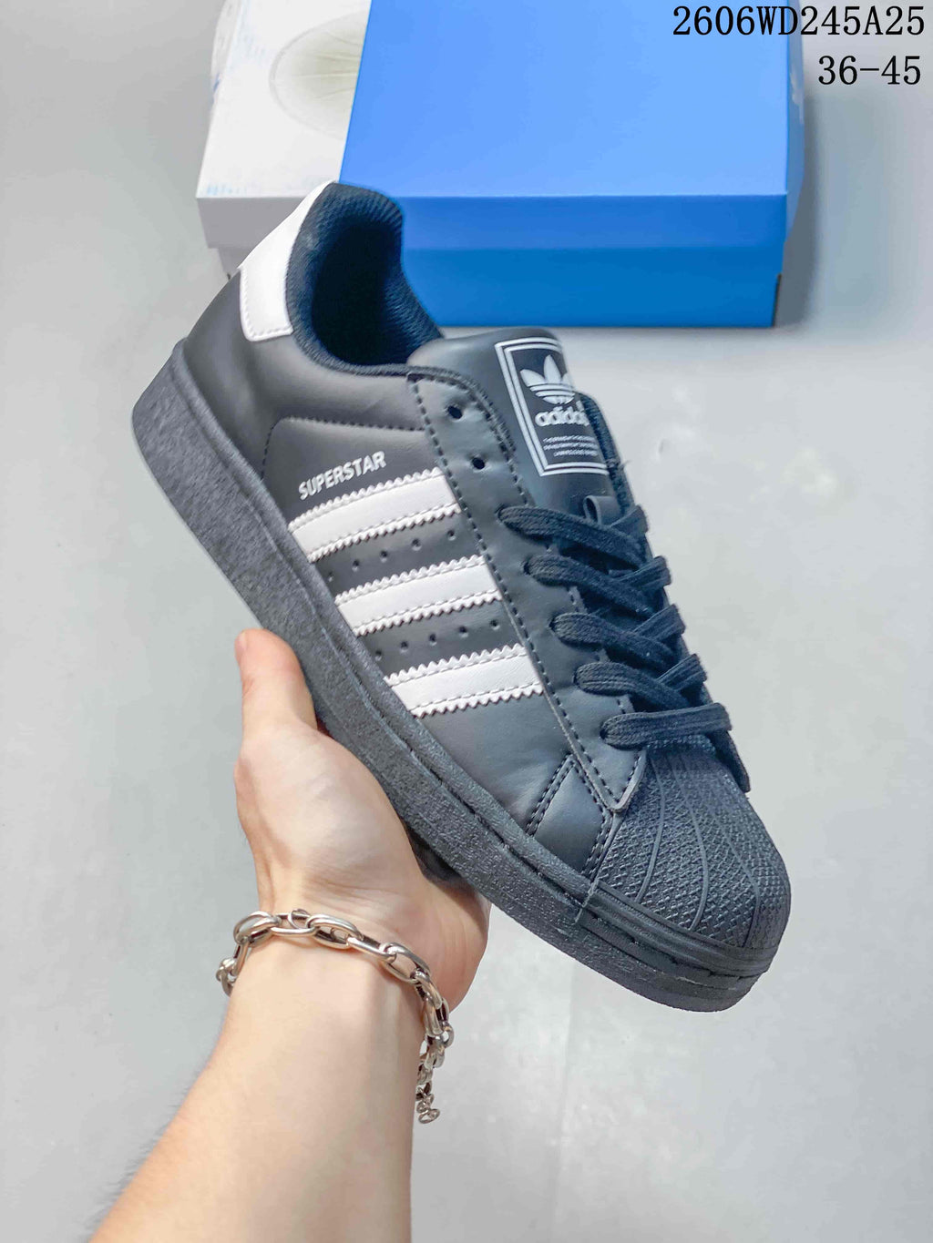 Angled side view of the charcoal Superstar sneaker with white stripes
