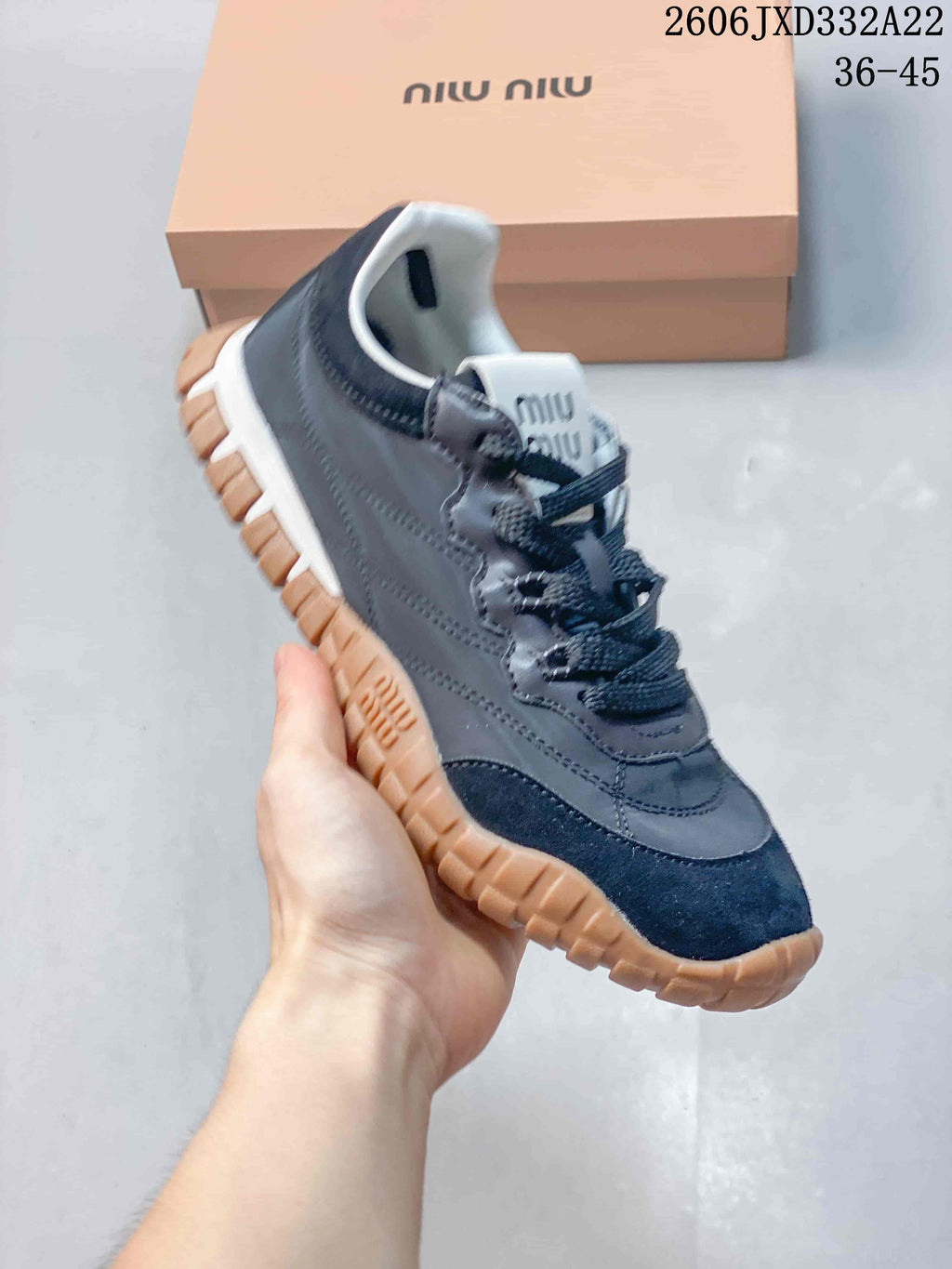 Angled side view of a gray and navy sneaker with a tan-colored outsole.
