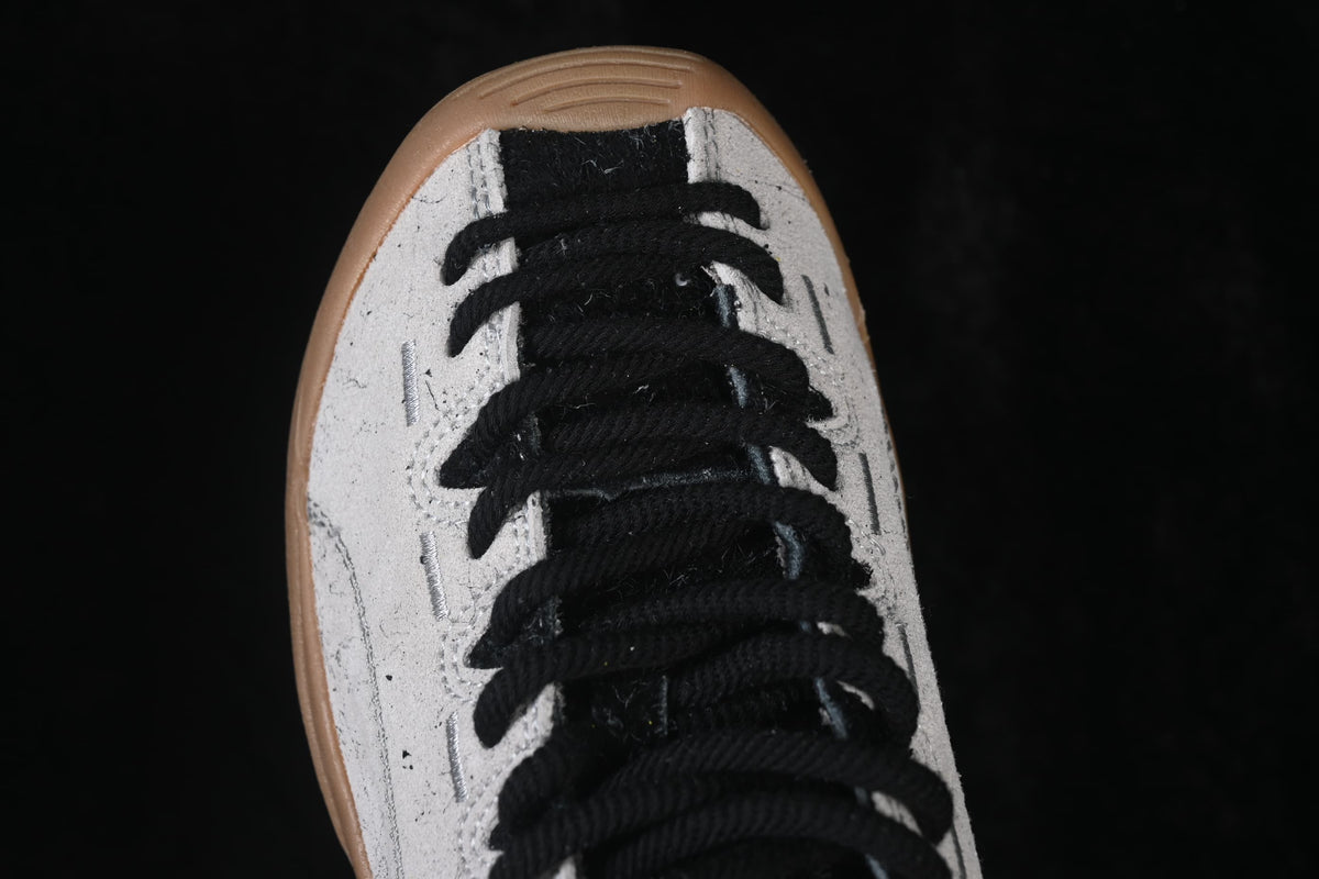 Top close-up of the sneaker's black laces and rounded toe.