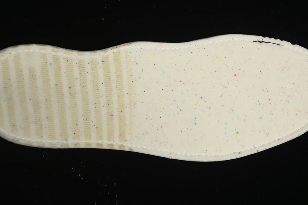 Underside view of the sneaker's light-colored insole with small colored speckles.
