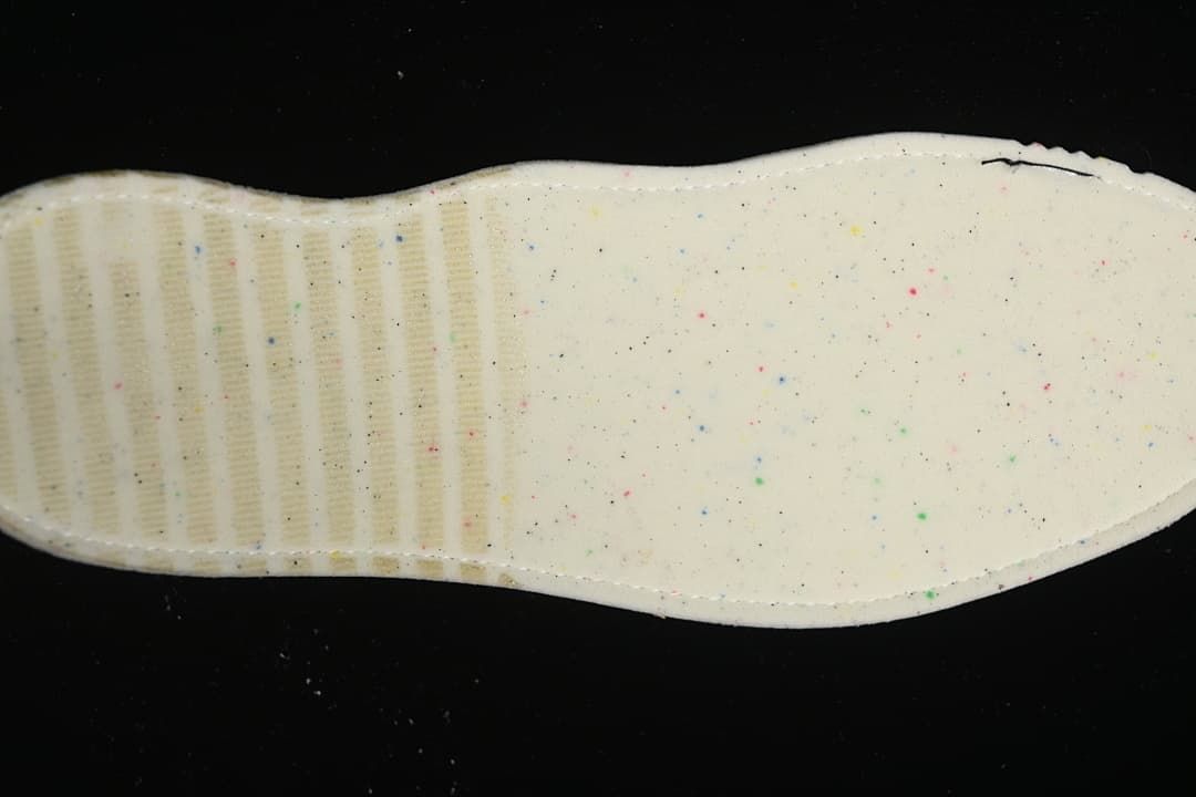 Underside view of the sneaker's light-colored insole with small colored speckles.