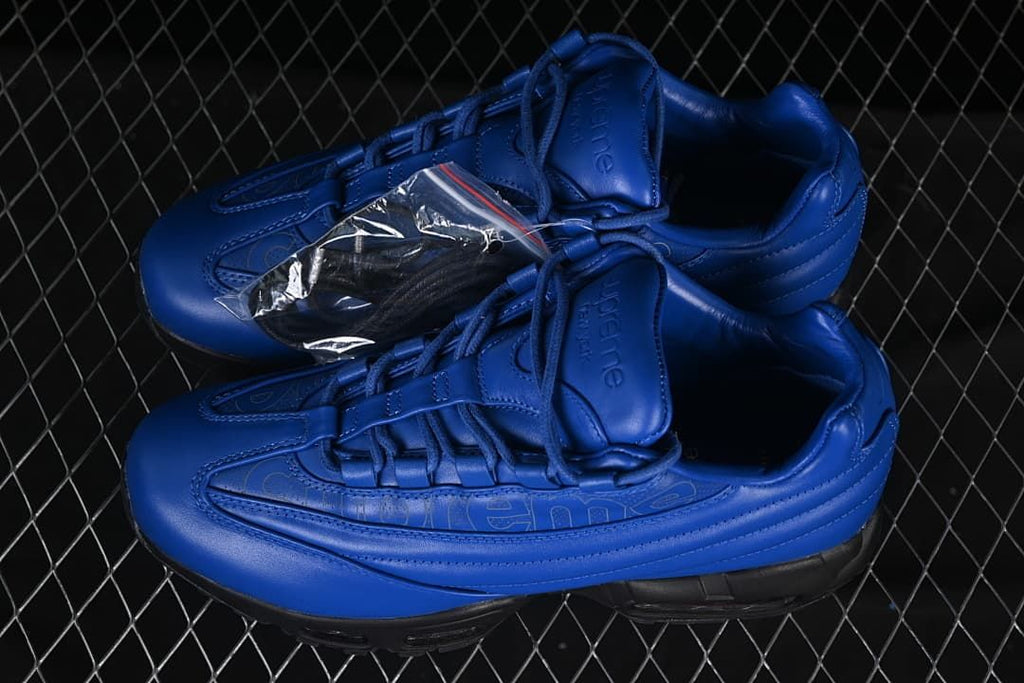Pair of blue sneakers with a small accessory packet shown alongside.