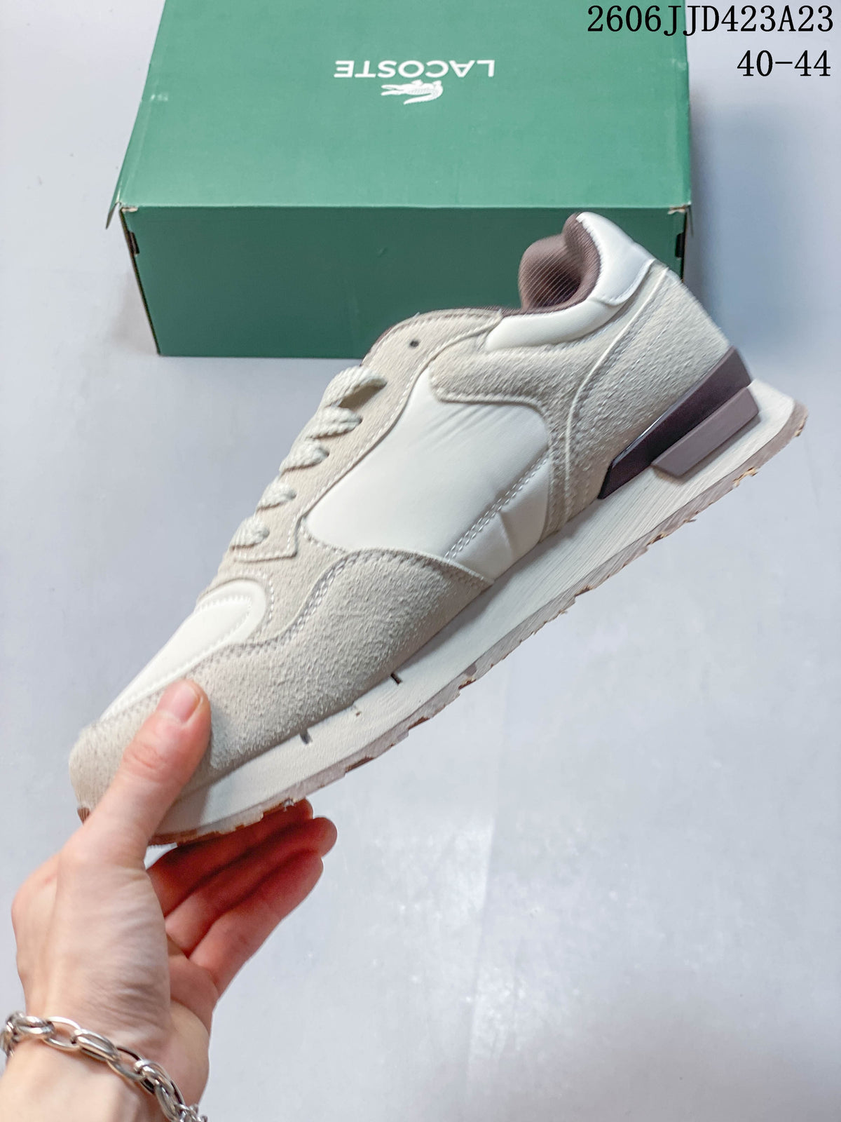 Side profile of the beige and off-white lace-up sneaker showing layered panels and heel accents.