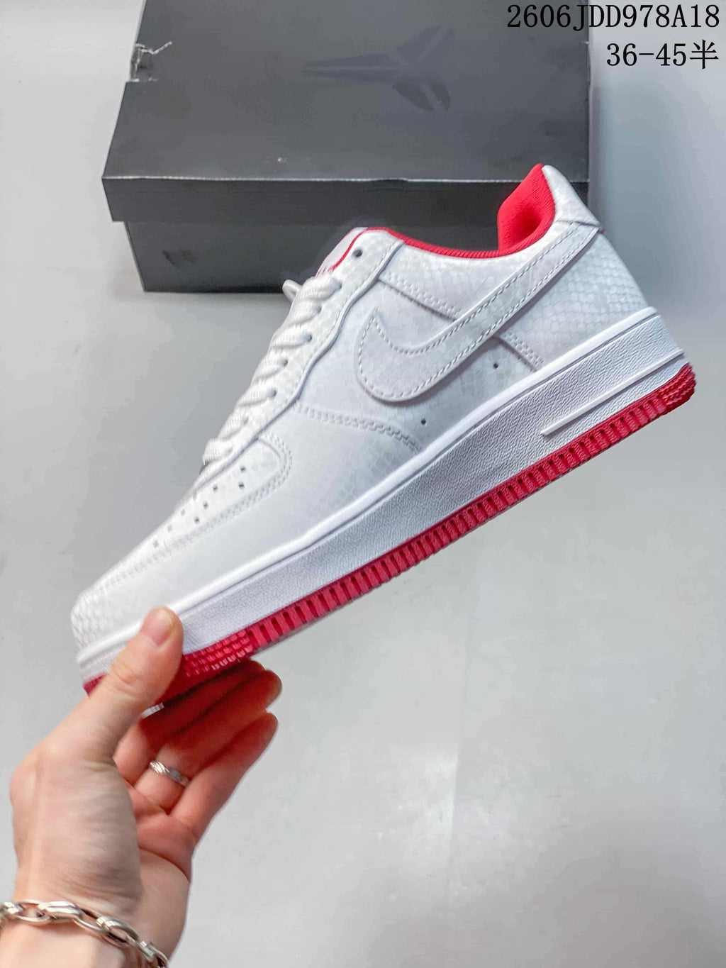 Side view of the white patterned sneaker with a red outsole