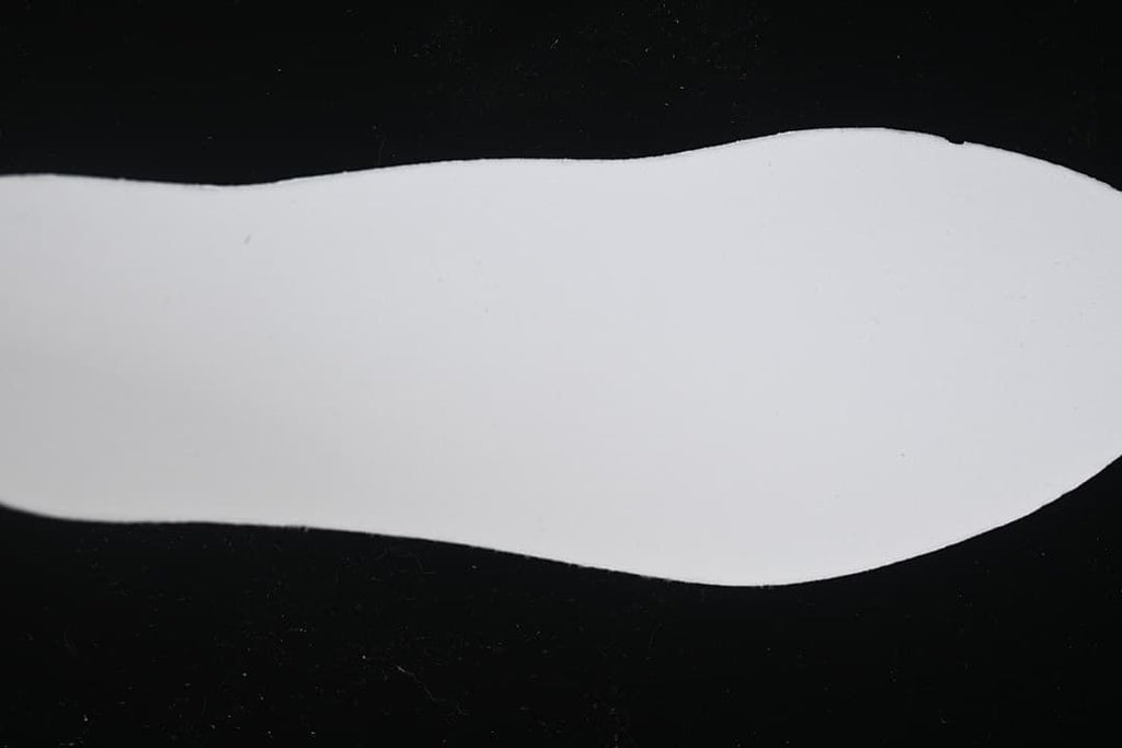 Plain white shoe-shaped insert photographed against a black background