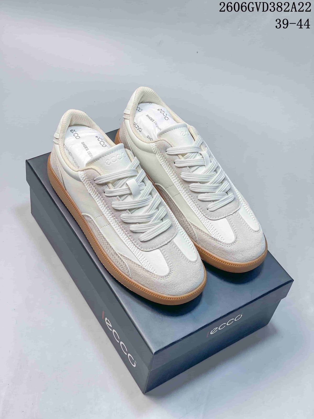Pair of light-colored ECCO-style lace-up sneakers with gum soles displayed on a shoe box