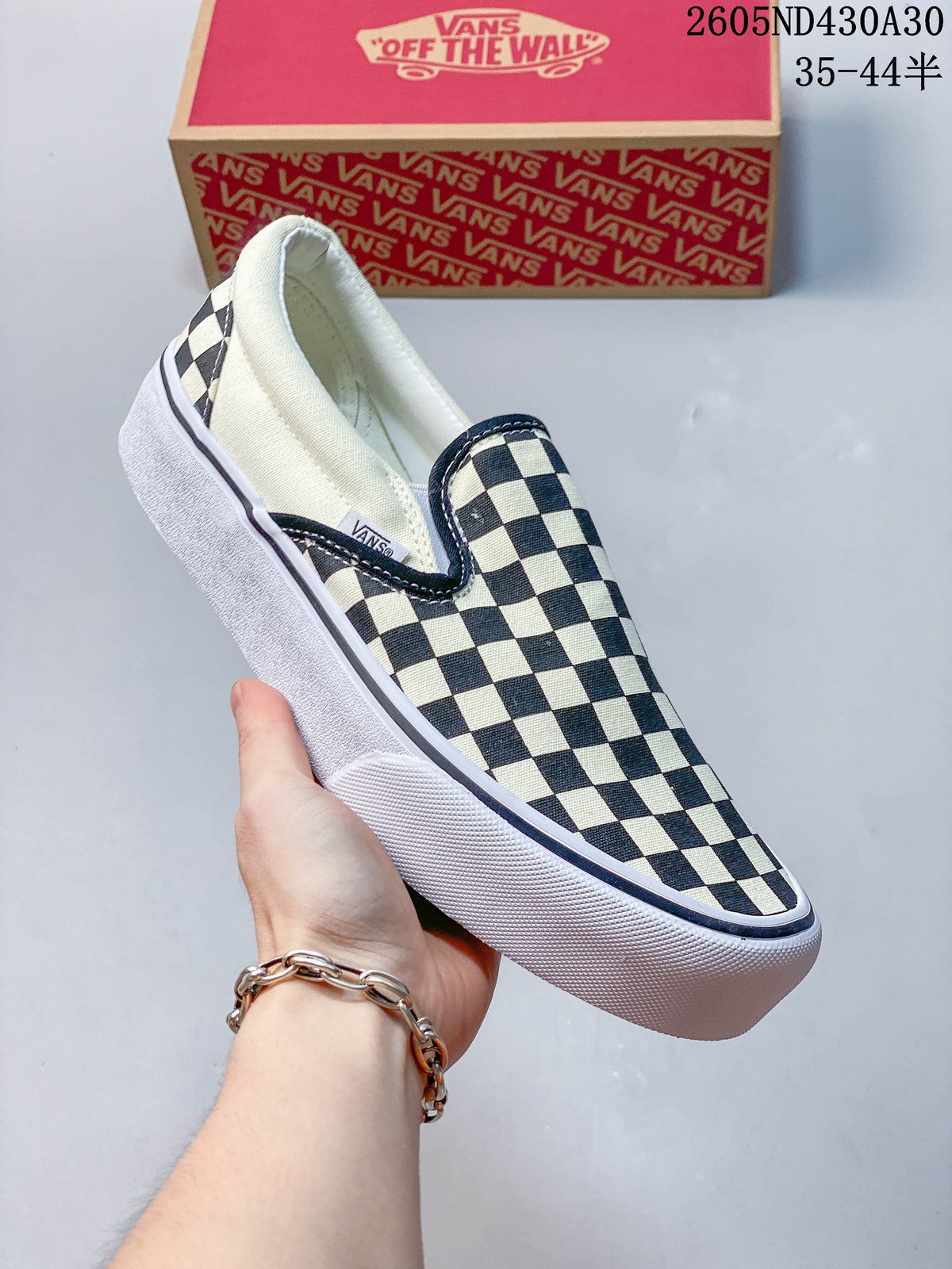 Angled view of a checkerboard slip-on sneaker with elastic side panels and a raised sole.