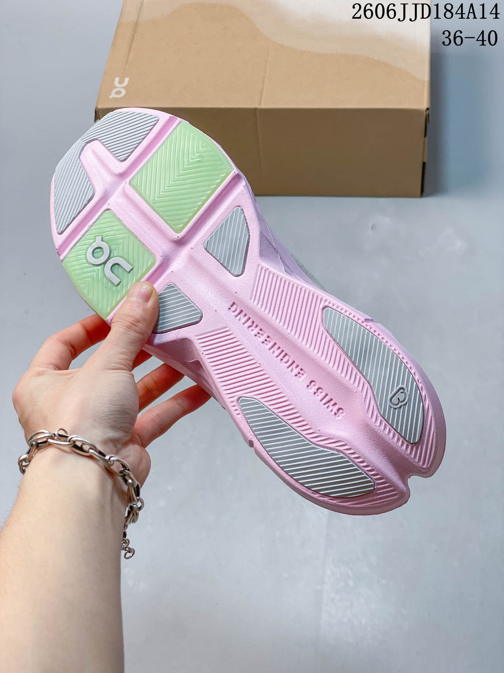 Underside of the sneaker showing a pink outsole with gray and green tread sections