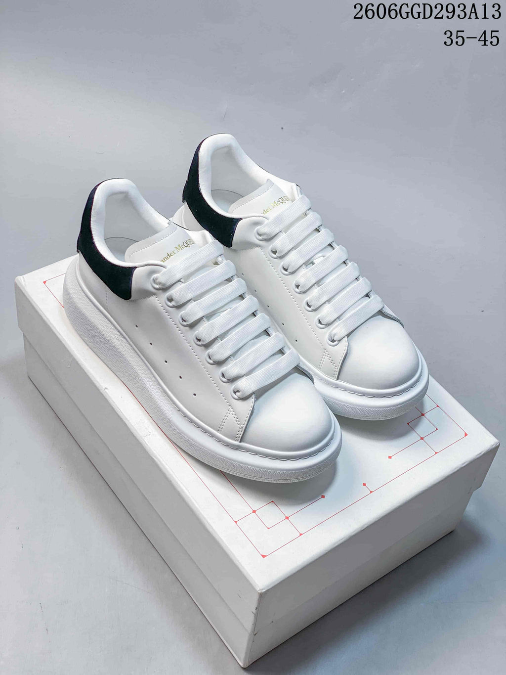 Pair of white low-top lace-up sneakers with black heel tabs and chunky white soles