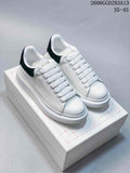 Pair of white low-top lace-up sneakers with black heel tabs and chunky white soles