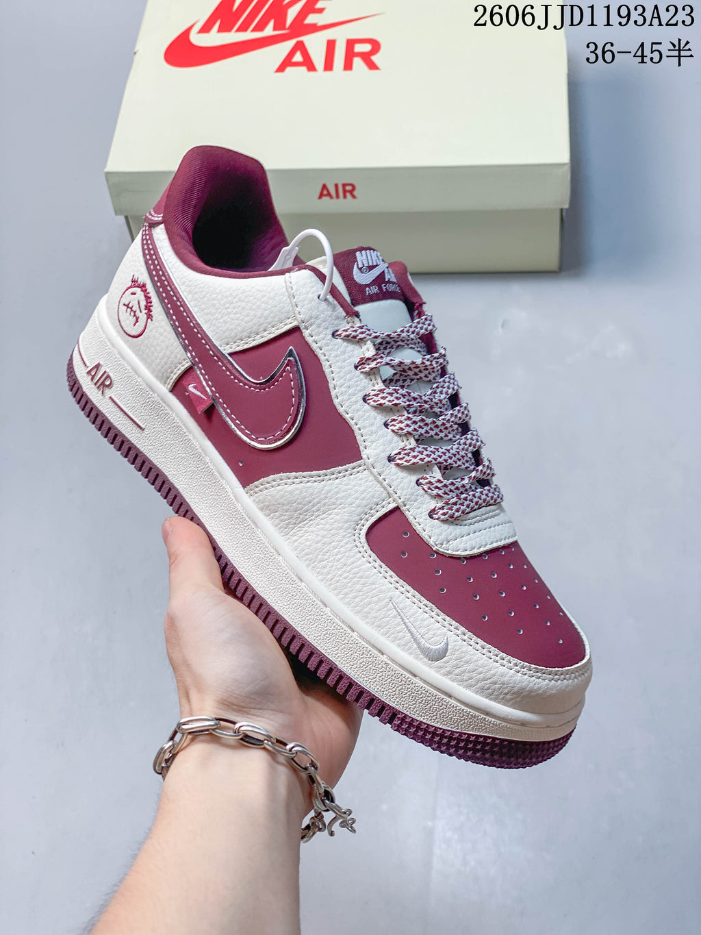 Close view of a white and burgundy sneaker with matching side Swoosh and laces