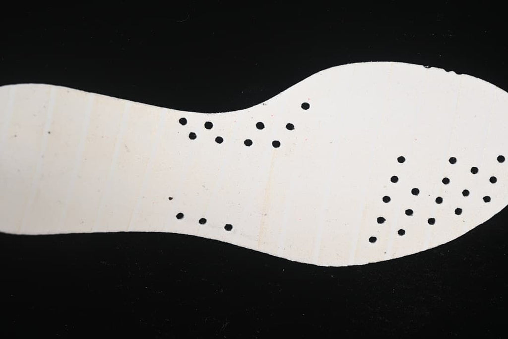 Light-colored shoe insert shown from the underside with perforations