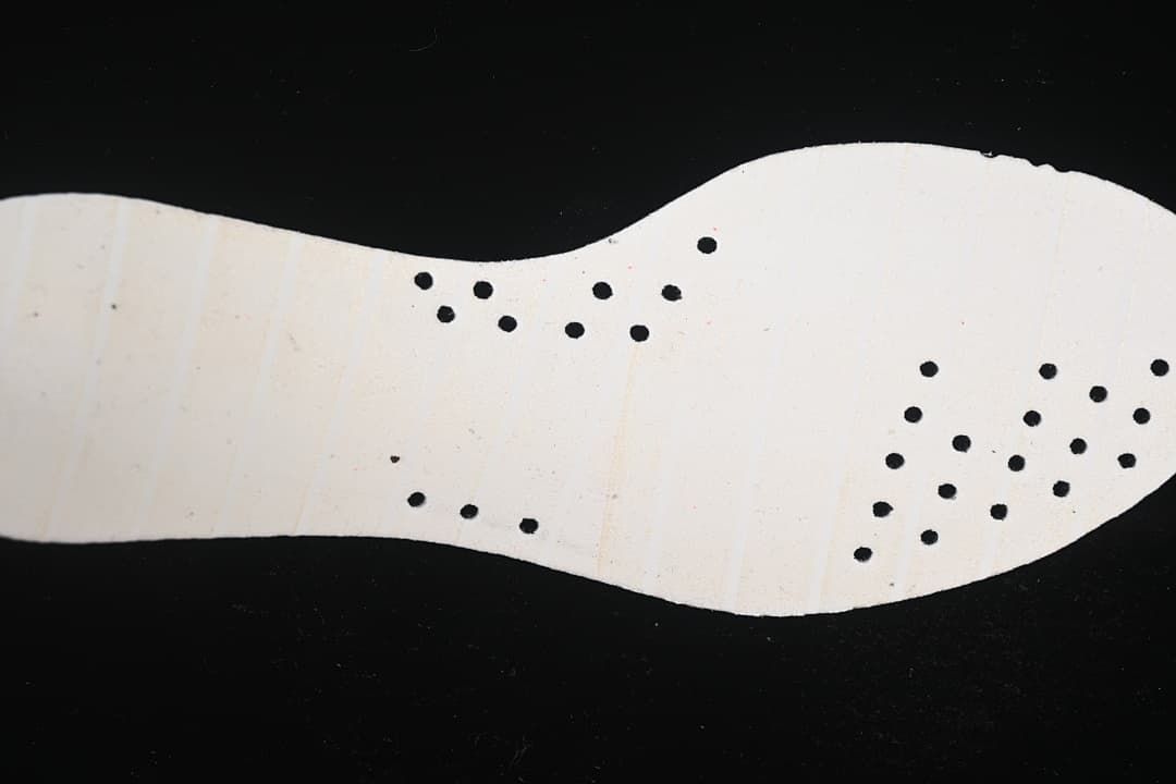 Light-colored shoe insert shown from the underside with perforations