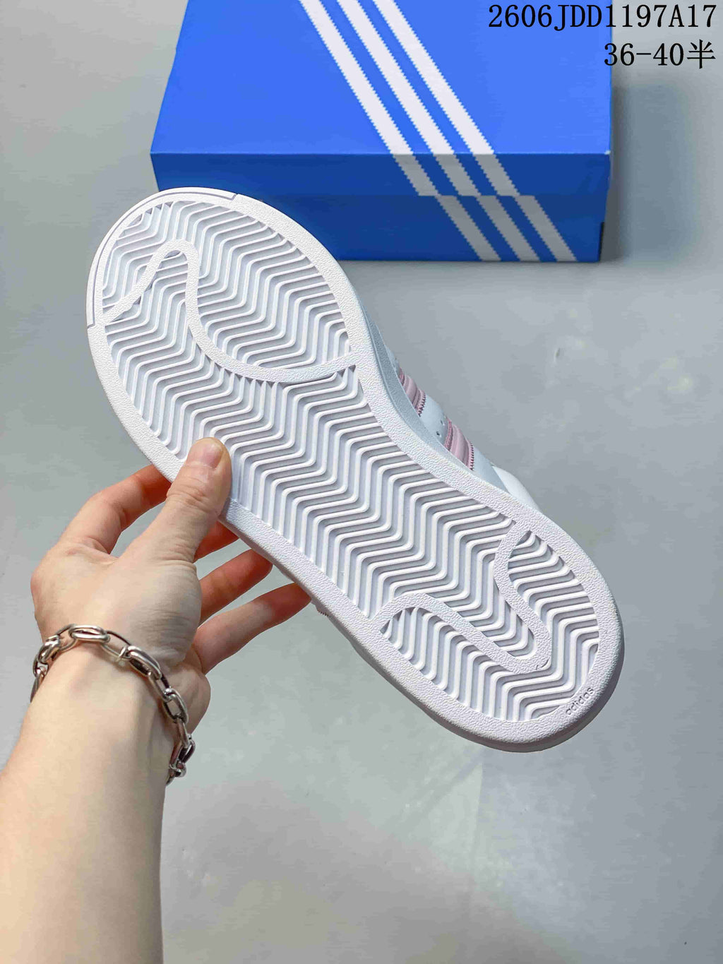 Underside of the white sneaker showing a patterned outsole and tread.