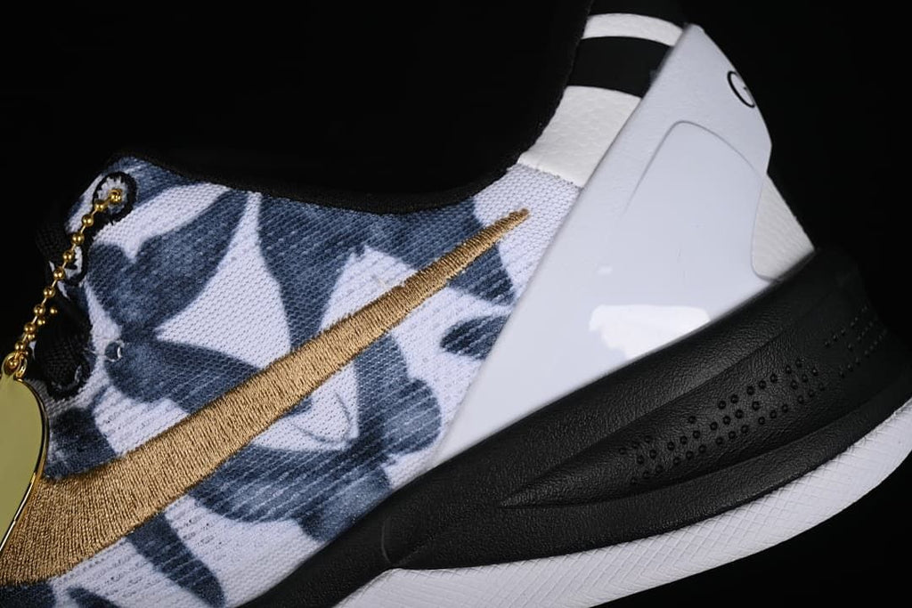 Close-up of the navy patterned upper, gold swoosh, white heel panel, and black midsole.