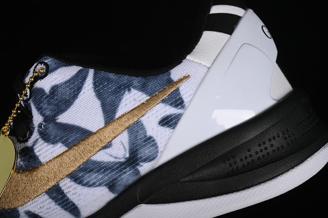 Close-up of the navy patterned upper, gold swoosh, white heel panel, and black midsole.