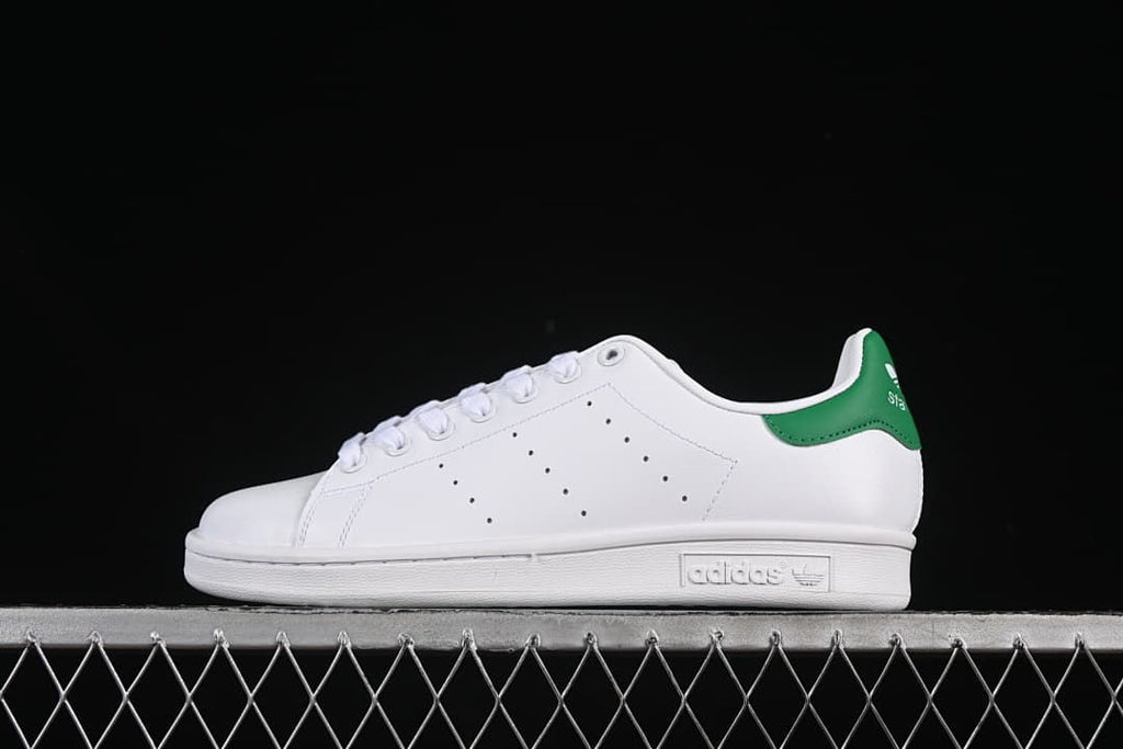 Side view of white adidas Stan Smith sneakers with a green heel tab