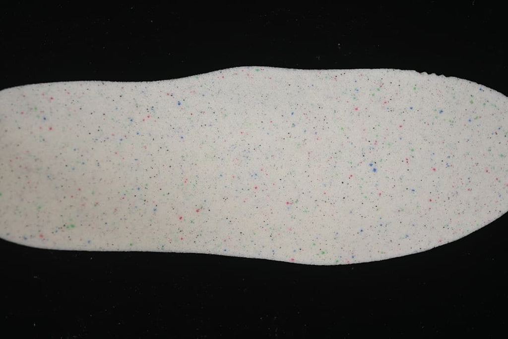 Light-colored insole shown from above with multicolored flecks.