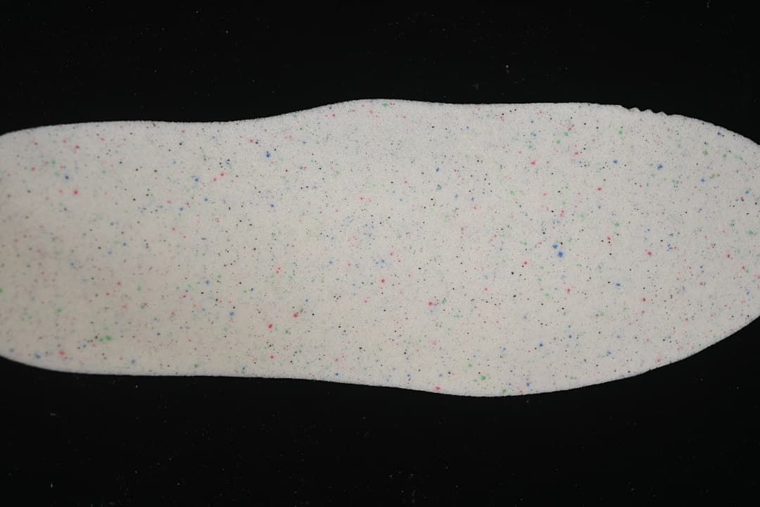 Light-colored insole shown from above with multicolored flecks.