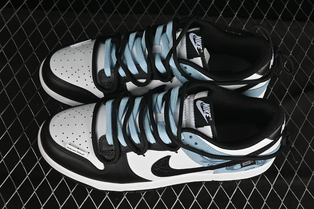 Top view of black, white, and pale blue Nike SB Dunk Low sneakers with contrasting laces.