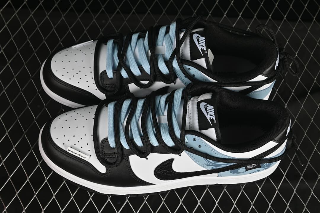 Top view of black, white, and pale blue Nike SB Dunk Low sneakers with contrasting laces.